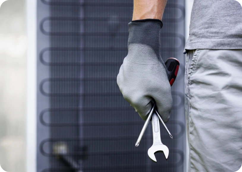 Technician holding tools near air conditioner.